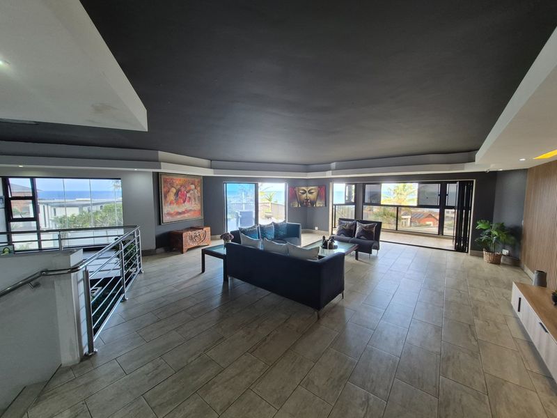 Spacious open-plan living area featuring large windows with ocean views, modern tiled flooring, and a contemporary dark ceiling design.