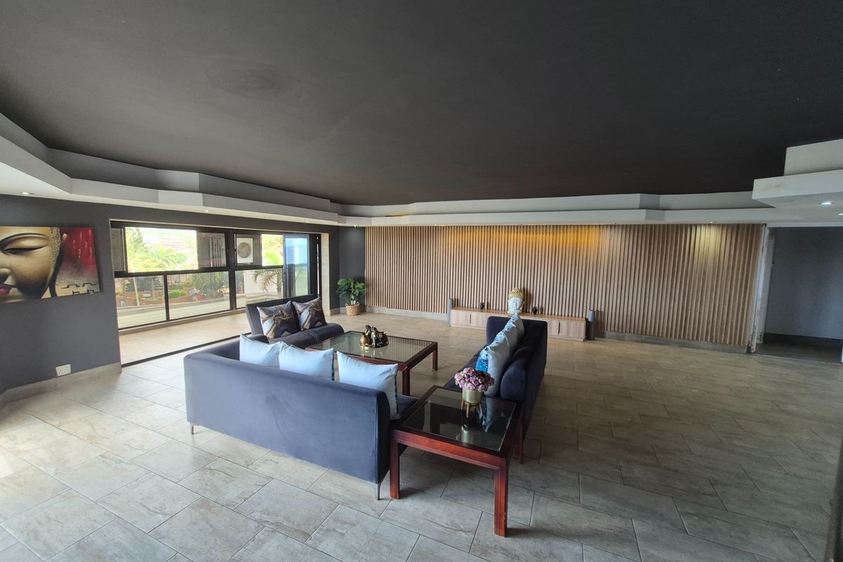 Spacious living area featuring modern tiled flooring, a striking timber slat feature wall, and large sliding glass doors leading to an outdoor space.