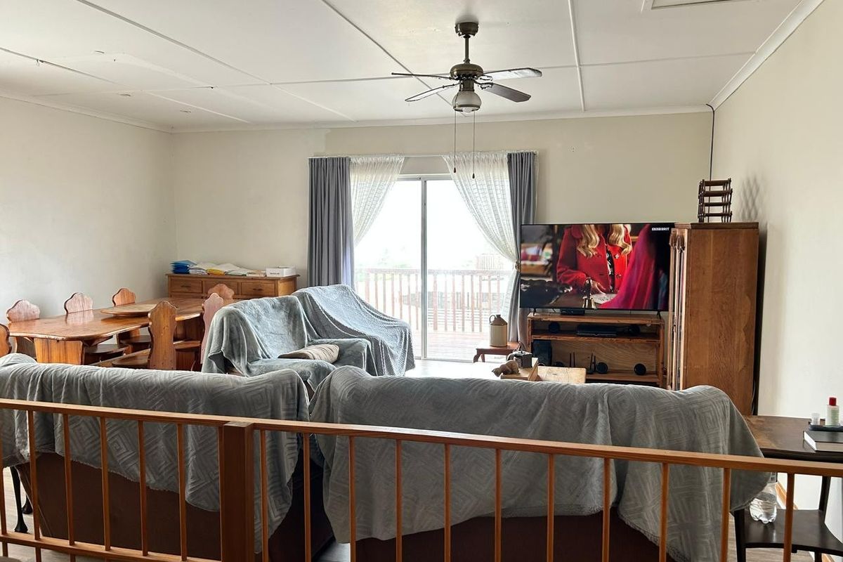 Spacious living area featuring a ceiling fan, laminate flooring, and a sliding glass door leading to an outdoor balcony.