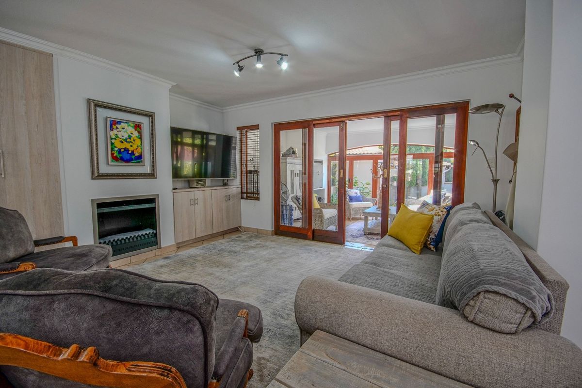A comfortable living room featuring a built-in fireplace, custom cabinetry, and large wooden sliding doors that open onto a covered patio area.
