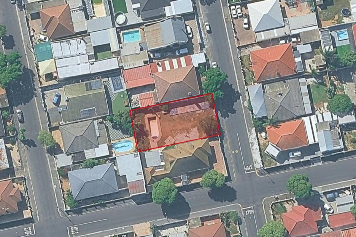 Aerial view of a residential plot featuring an existing swimming pool and cleared land area within a suburban neighborhood.