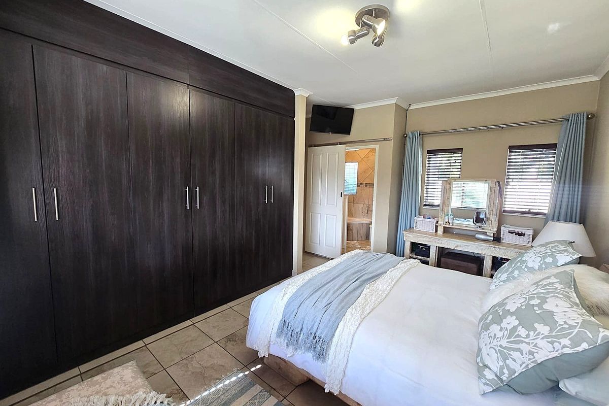 Spacious bedroom featuring extensive built-in dark wood cabinetry, tiled flooring, and an en-suite bathroom access.
