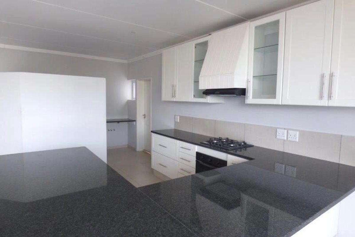 Modern kitchen featuring white cabinetry, dark granite countertops, built-in oven, gas hob, and a tiled backsplash in a clean, open-plan layout.