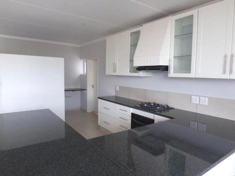 Modern kitchen featuring white cabinetry, dark granite countertops, built-in oven, gas hob, and a tiled backsplash in a clean, open-plan layout.