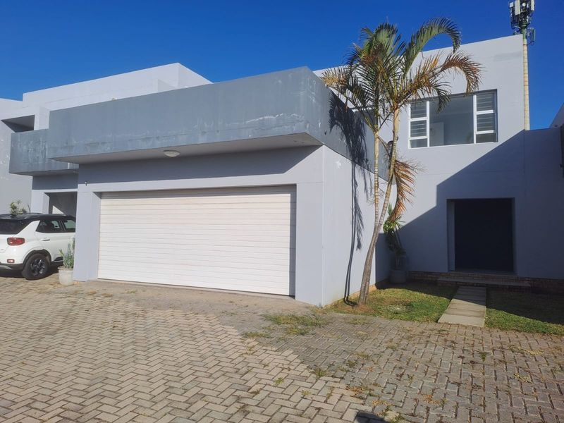 Front elevation of a modern house featuring a double garage, paved driveway, and clean architectural lines.