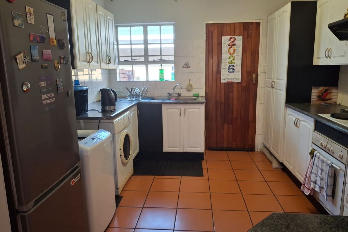 Functional kitchen featuring white cabinetry, tiled flooring, built-in oven and hob, and a practical layout with integrated laundry plumbing.