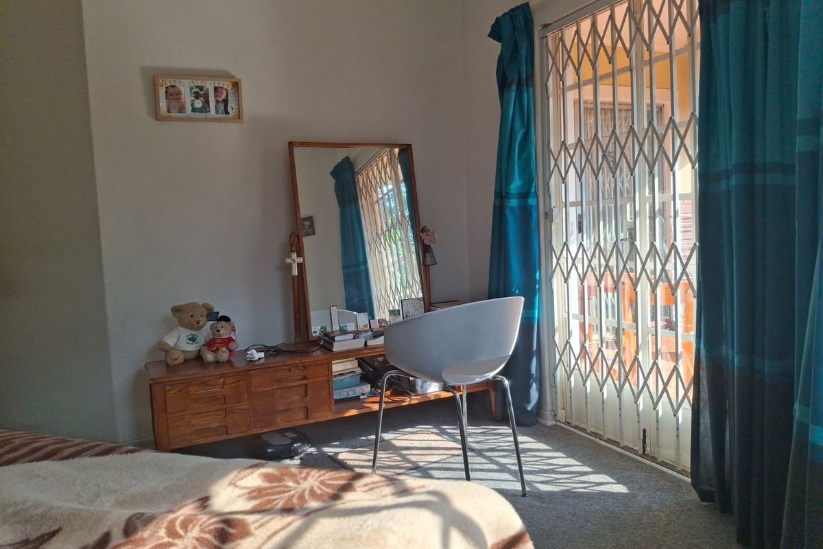 A bedroom featuring carpet flooring and a sliding door with a fitted security gate, providing access to an outdoor area.