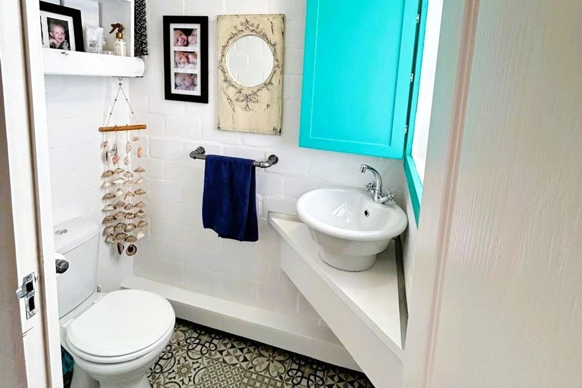 A compact bathroom featuring a corner vanity with a vessel sink, a standard toilet, and patterned floor tiles.