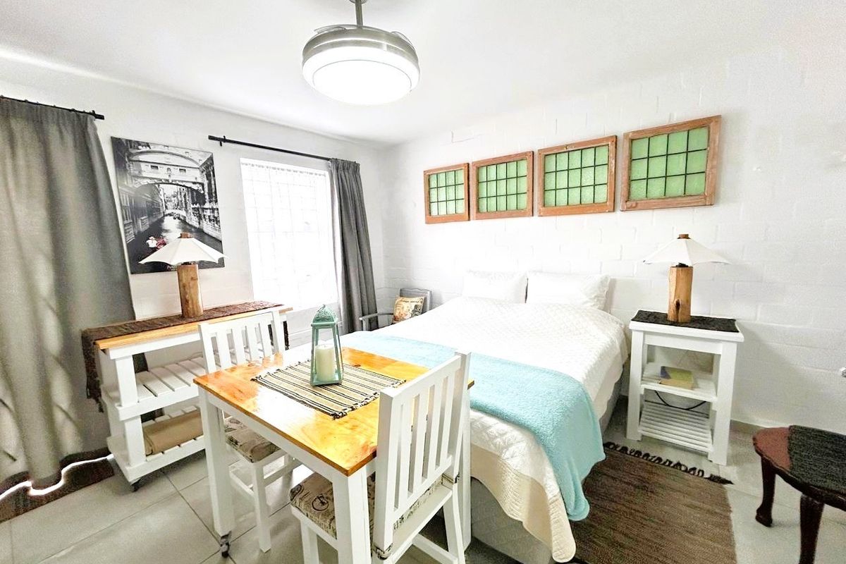 A bedroom featuring painted brick walls, tiled flooring, and a central ceiling fan light fixture.