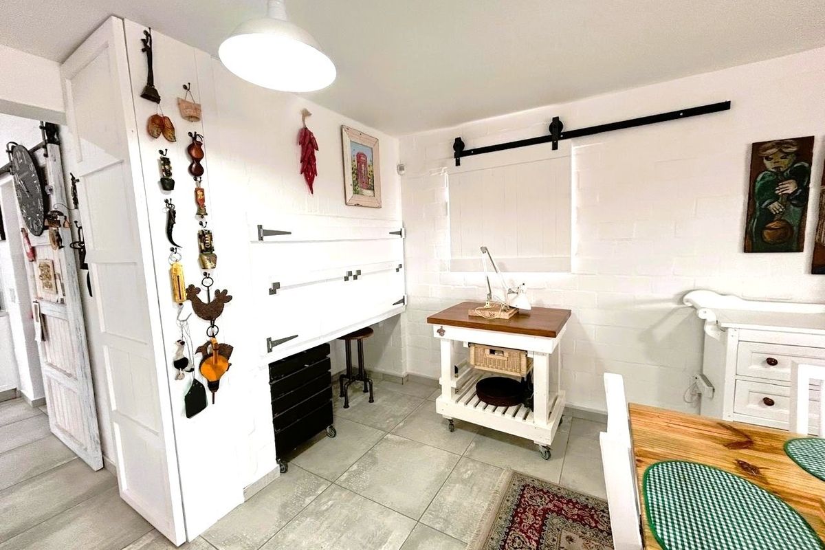 A functional kitchen area featuring tiled flooring, white painted brick walls, and a sliding barn-style door mechanism.