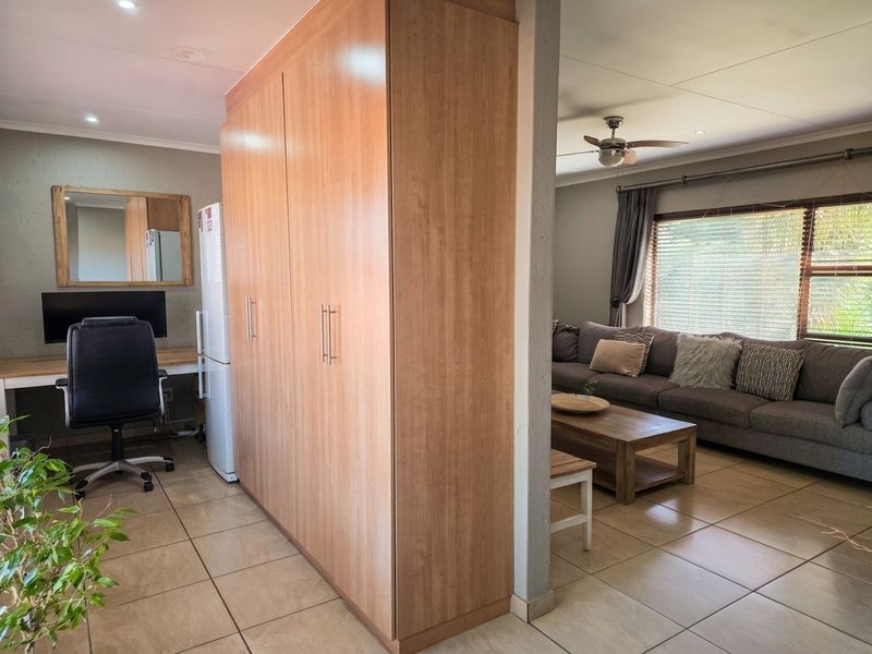 Open plan living area featuring tiled flooring, built-in cabinetry, and a dedicated workspace area with recessed lighting.