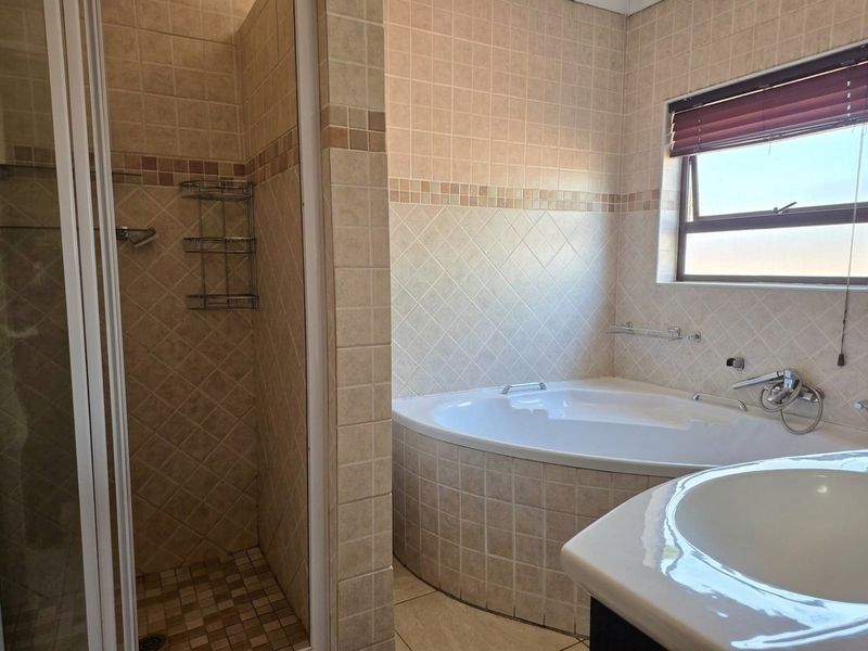 A functional bathroom featuring a corner bathtub, a separate shower enclosure with tiled walls, and a vanity basin.