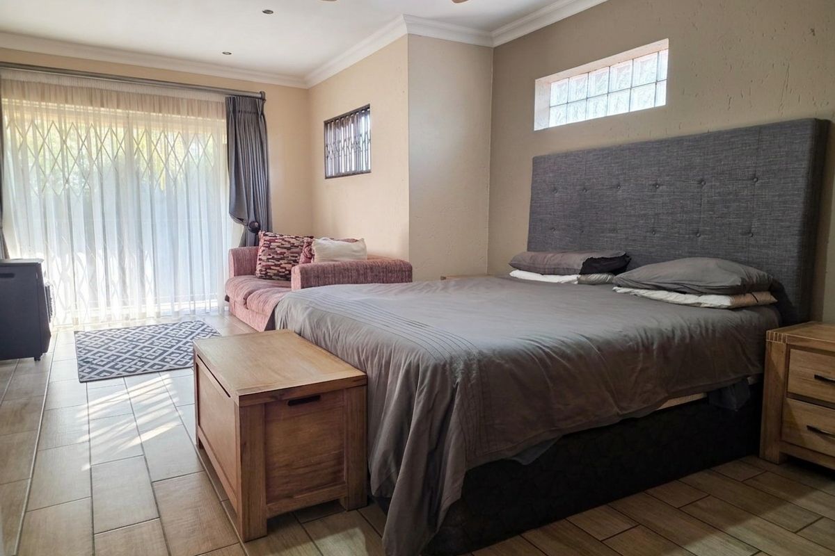 Spacious bedroom featuring tiled flooring, a ceiling fan, and a sliding door with security gate providing access to the exterior.