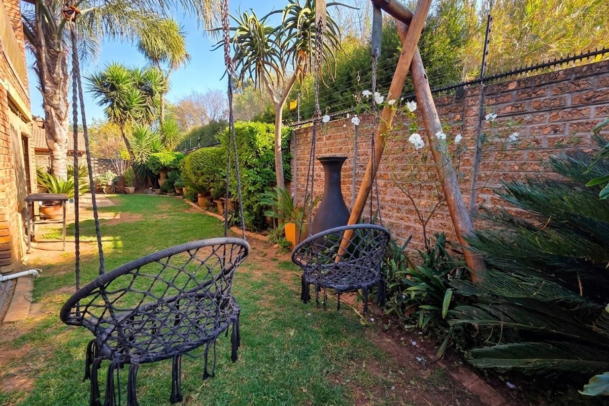 A private rear garden featuring a lawn, established landscaping, and a brick boundary wall with integrated security fencing.