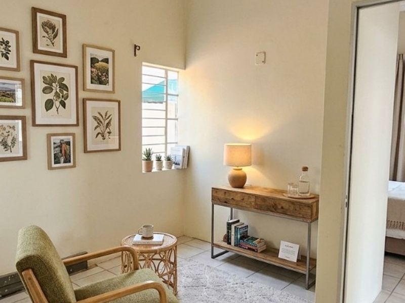 A cozy living area featuring neutral tiled flooring, a steel frame window, and a simple flush mount ceiling light fixture.
