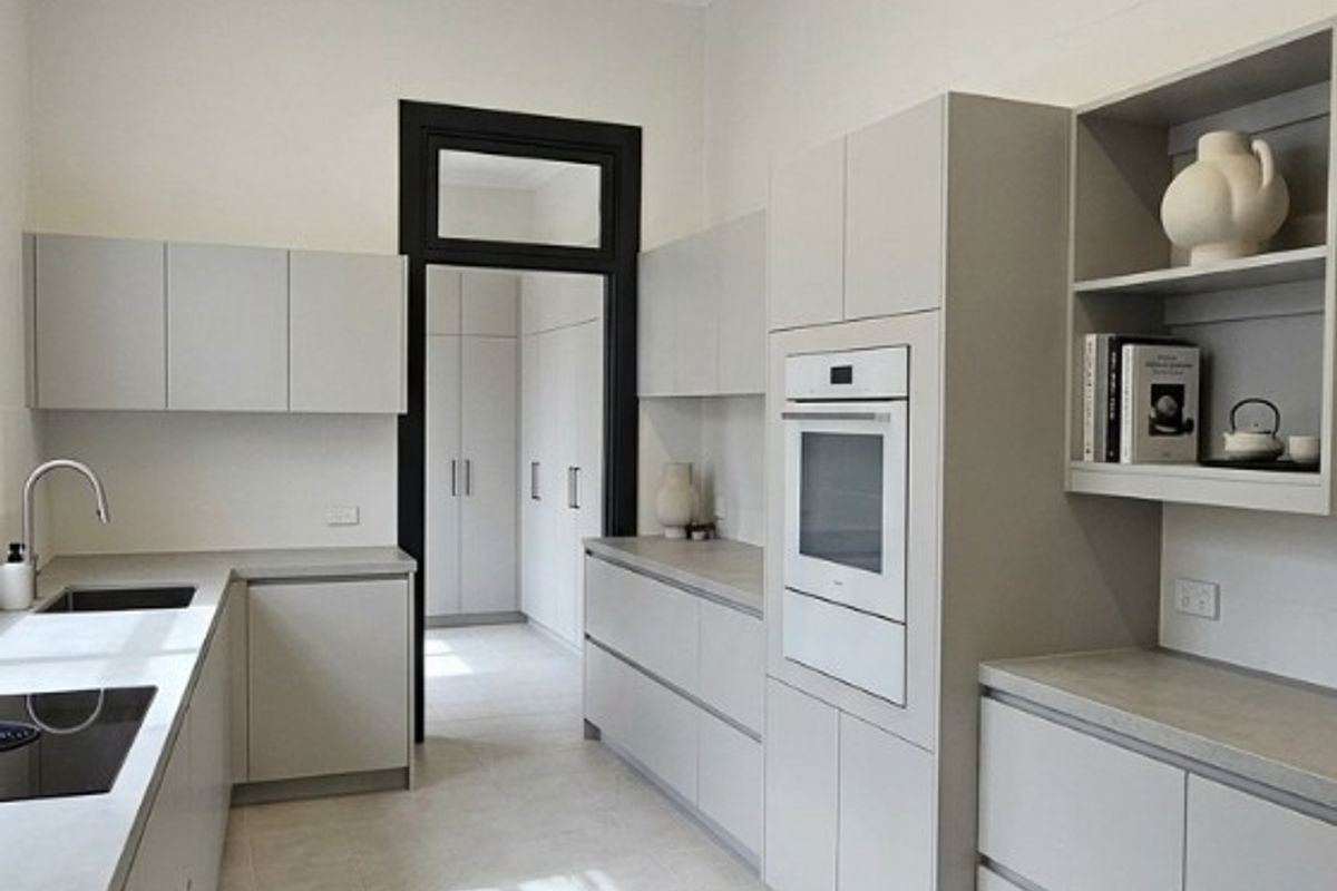 Modern galley-style kitchen featuring sleek cabinetry, integrated oven, stone-look countertops, tiled flooring, and a decorative pressed metal ceiling.
