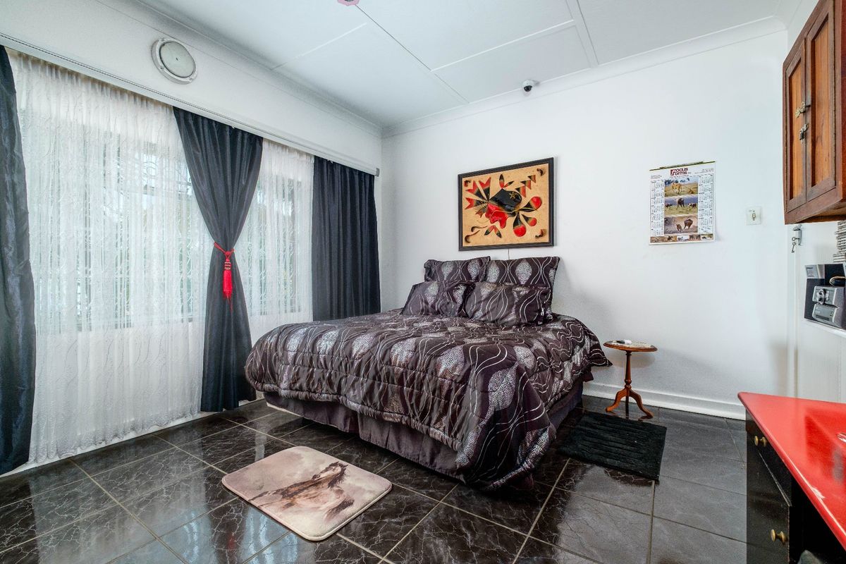 A bedroom featuring dark tiled flooring, large window with curtains, and built-in cabinetry.