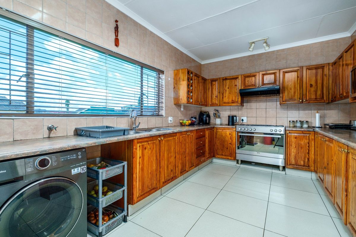 A functional kitchen featuring wooden cabinetry, tiled splashbacks, tiled flooring, and a built-in oven with an extractor fan.