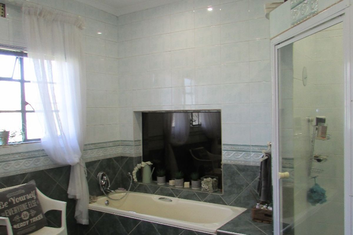 A functional bathroom featuring a built-in bathtub with tiled surround, a separate shower enclosure, and tiled flooring.