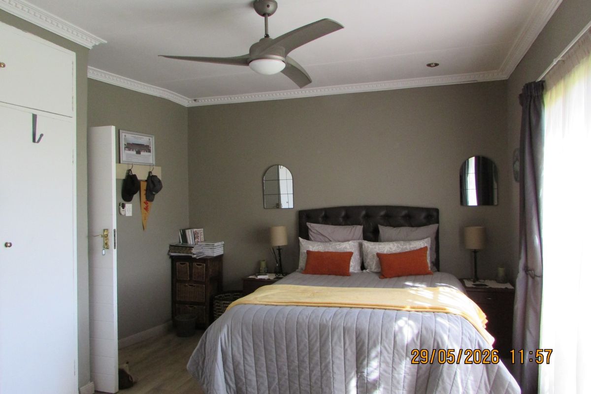 A well-maintained bedroom featuring built-in cupboards, crown molding, and a modern ceiling fan, offering a comfortable and functional living space.