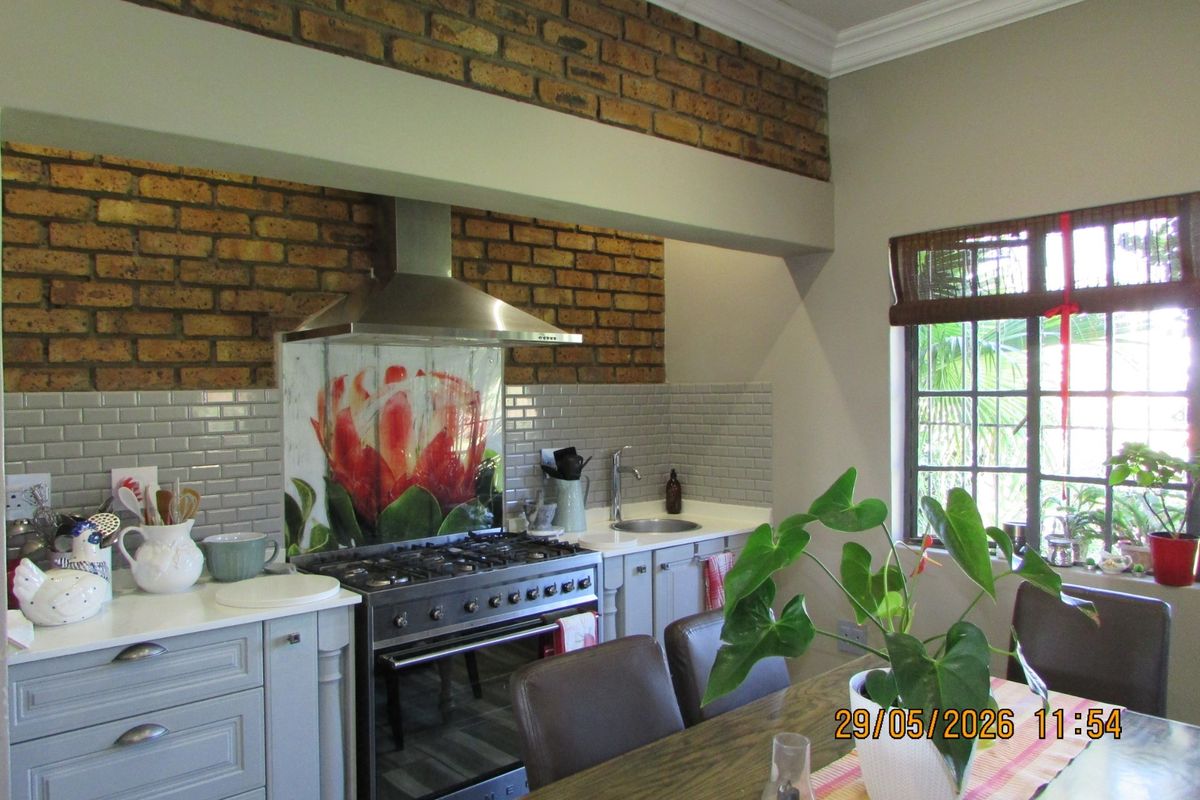 A charming kitchen featuring exposed brickwork, subway tile backsplash, a stainless steel gas range with extractor fan, and light grey cabinetry.