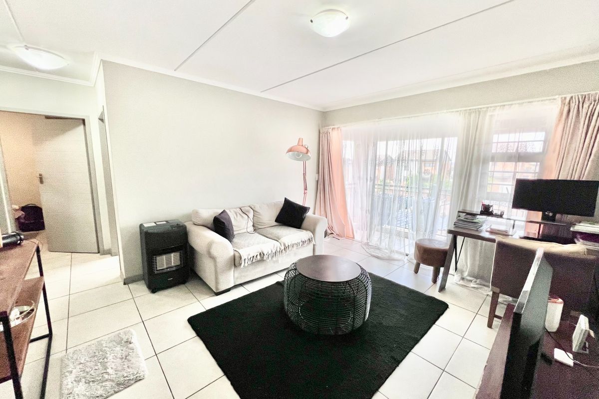 A bright living room featuring tiled flooring and a large sliding glass door providing access to the balcony area.