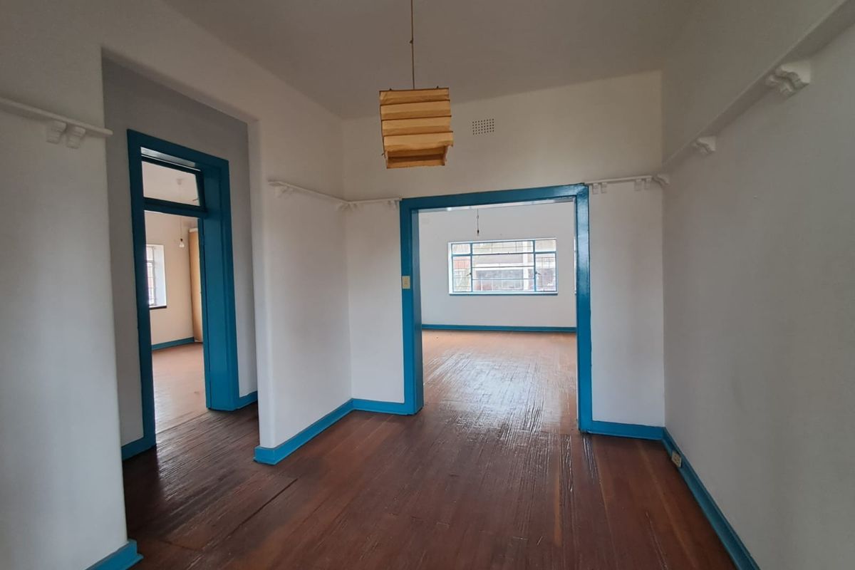 An empty living area featuring original timber flooring, high ceilings, and blue-painted door frames, offering a blank canvas for renovation.