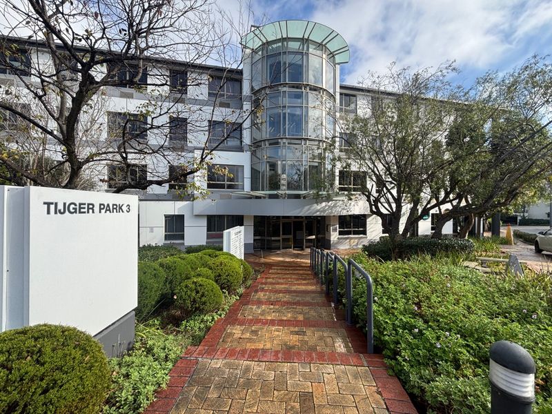 Front exterior view of Tijger Park 3 office building featuring a prominent glass facade, paved entrance walkway, and established landscaped gardens.