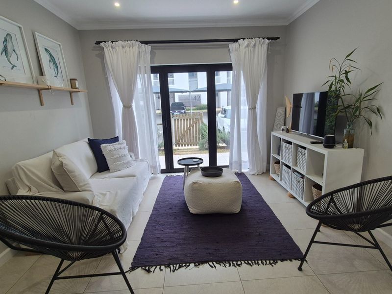 A well-maintained living room featuring tiled flooring, recessed downlighting, and a sliding glass door providing access to the exterior.