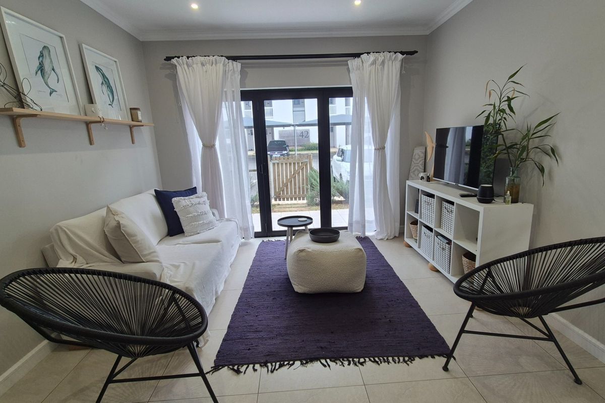 A well-maintained living room featuring tiled flooring, recessed downlighting, and a sliding glass door providing access to the exterior.