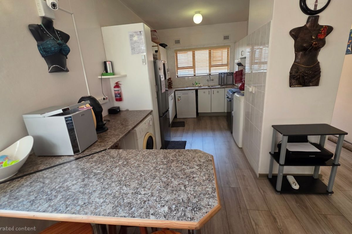 A functional kitchen featuring laminate countertops, built-in cabinetry, a stainless steel sink, and integrated space for laundry appliances.