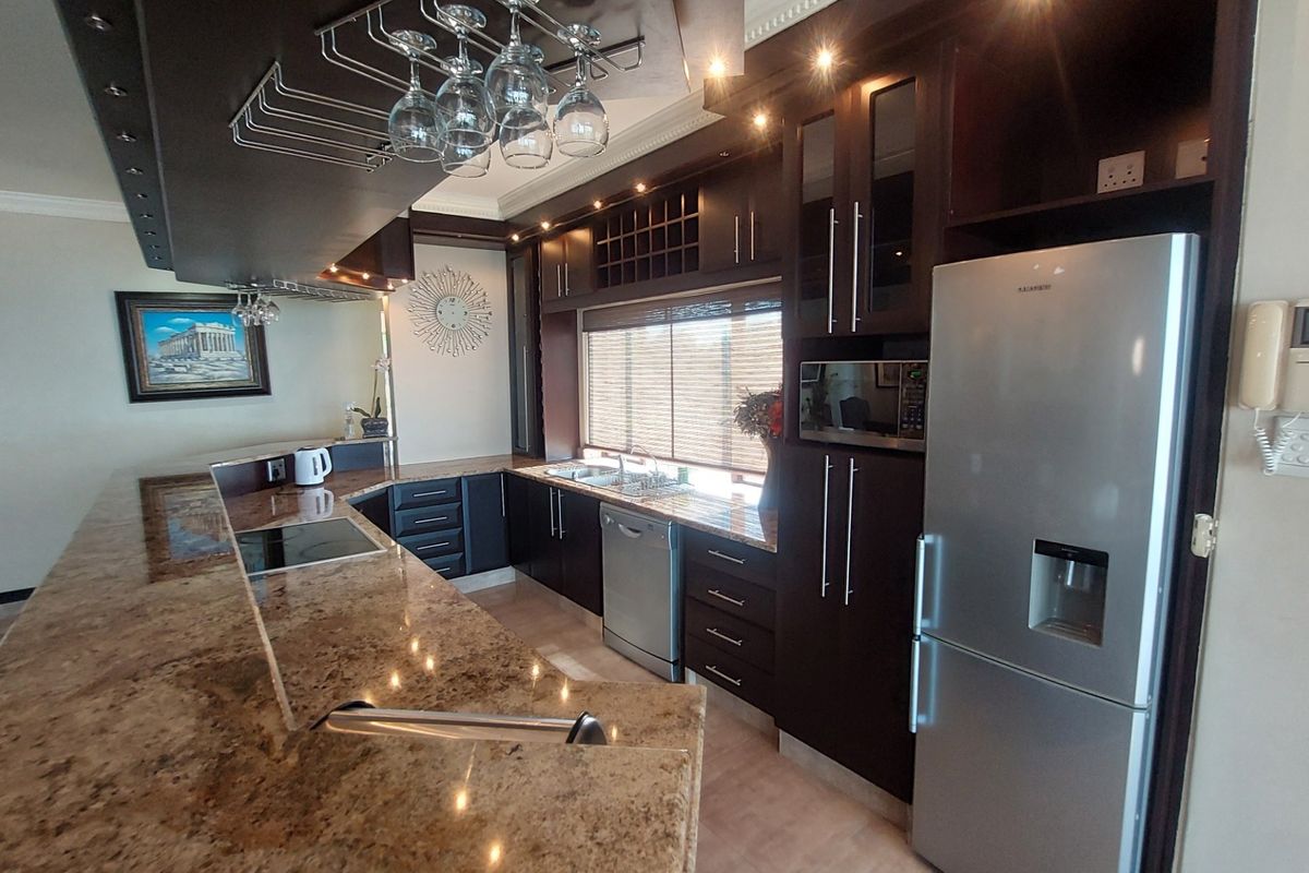 Modern kitchen featuring dark wood cabinetry, granite countertops, integrated wine rack, and built-in stainless steel appliances.