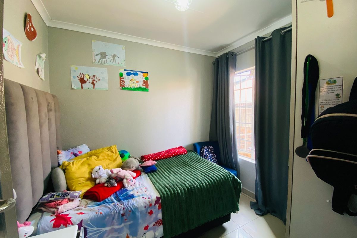 A functional bedroom featuring tiled flooring, a window with curtain tracks, and a built-in cupboard.