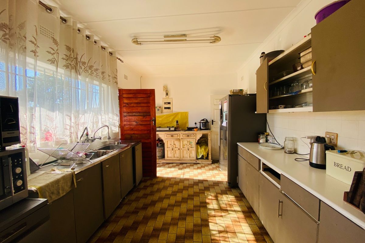 A functional galley-style kitchen featuring built-in cabinetry, a double sink, and tiled flooring, offering a practical layout with potential for modernization.