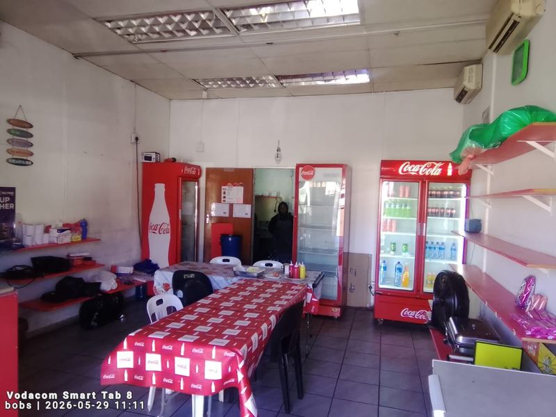 Open-plan commercial space featuring tiled flooring, suspended ceiling, and wall-mounted air conditioning, suitable for a retail or food service setup.