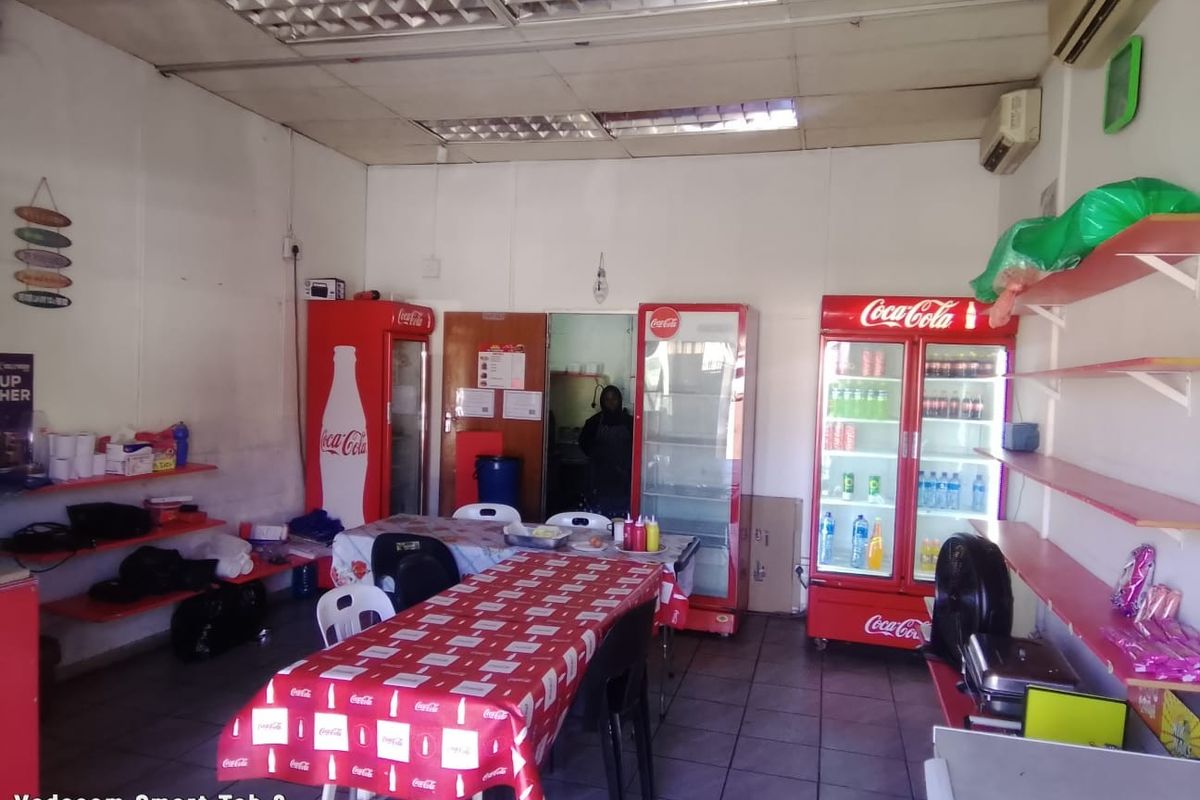 Open-plan commercial space featuring tiled flooring, suspended ceiling, and wall-mounted air conditioning, suitable for a retail or food service setup.