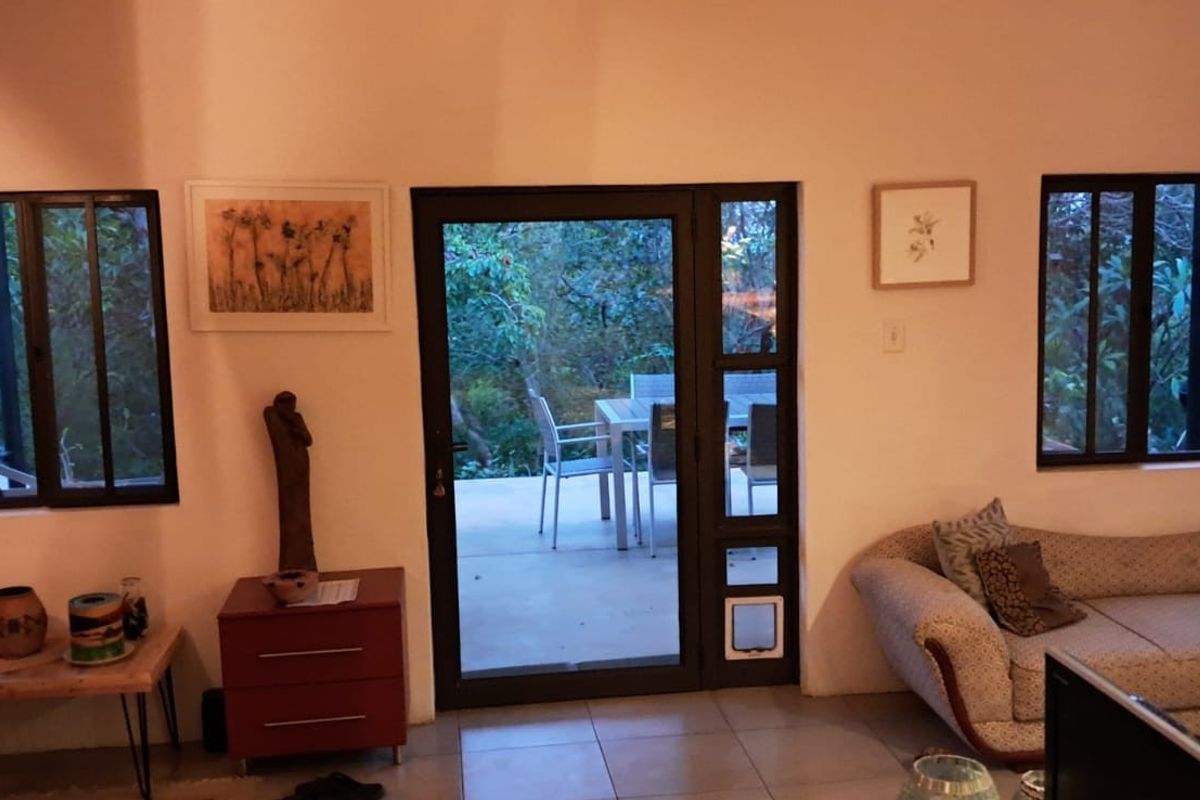 A living room featuring large windows and a glass door providing direct access to an outdoor patio area.