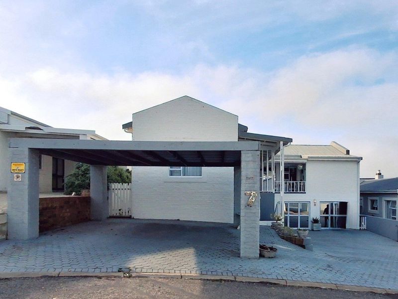 Front exterior view of the property featuring a covered carport, paved driveway, and white painted brick facade.