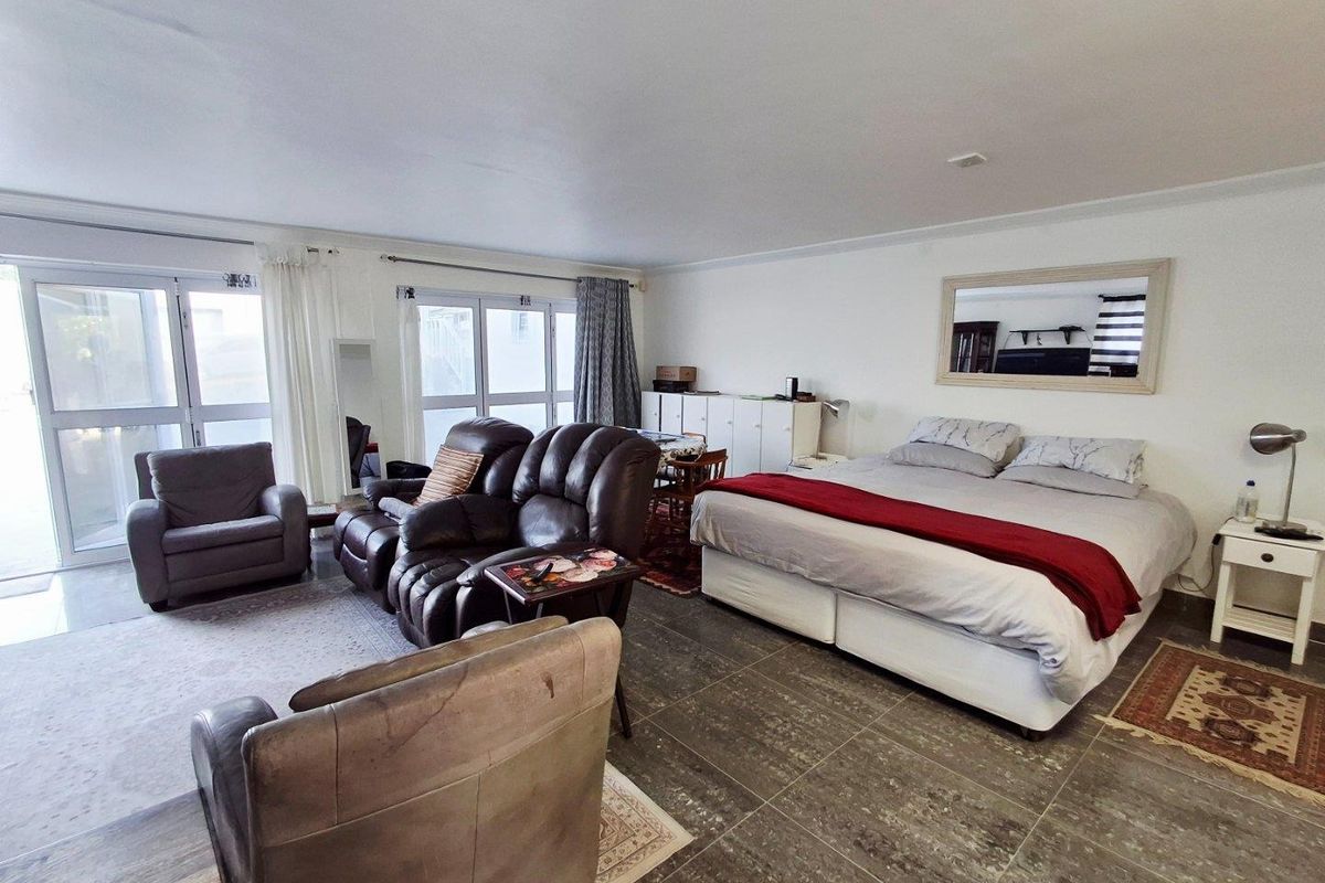Spacious bedroom featuring large glass sliding doors providing natural light and direct access to the exterior, complemented by tiled flooring.