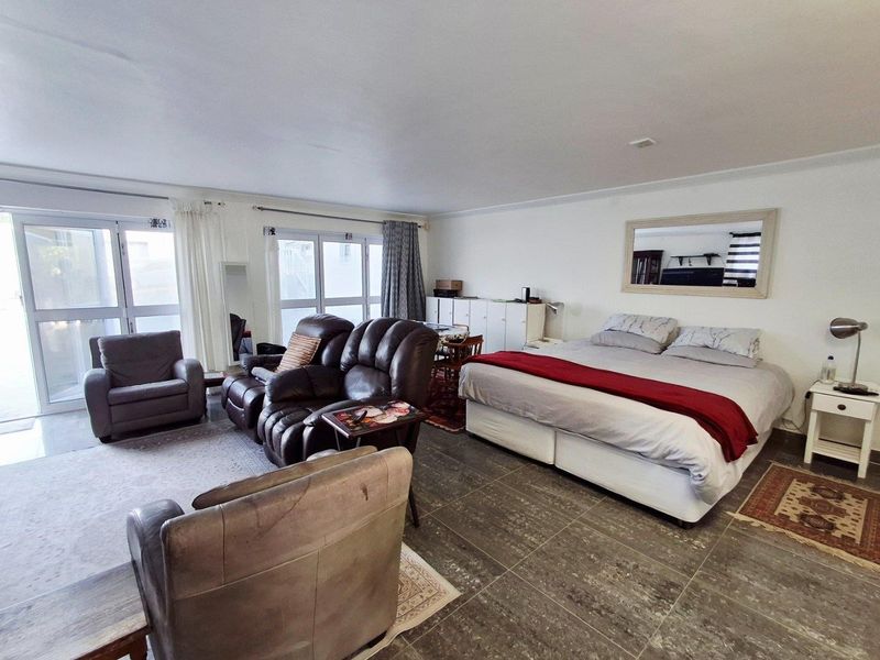 Spacious bedroom featuring large glass sliding doors providing natural light and direct access to the exterior, complemented by tiled flooring.