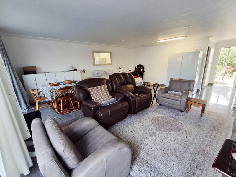 A spacious open-plan living area featuring tiled flooring and direct access to an outdoor patio space.