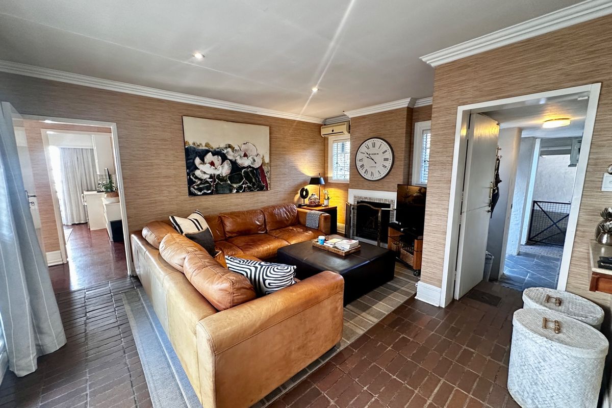 A cozy living room featuring a built-in fireplace, textured wallpaper, and terracotta tile flooring, with direct access to adjacent living spaces.