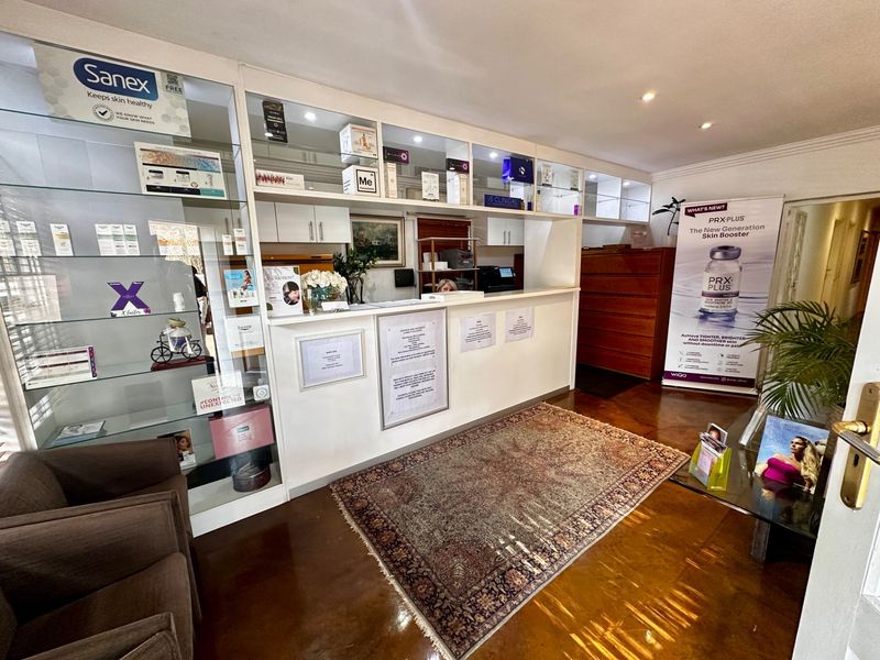 A commercial reception area featuring built-in display cabinetry, a service counter, and polished wooden flooring.