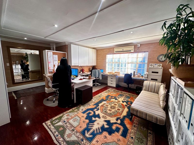 A functional home office space featuring built-in cabinetry, a long desk workstation, recessed lighting, and a wall-mounted air conditioning unit.