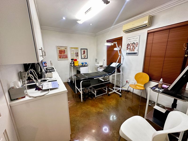 A functional treatment room featuring polished concrete flooring, built-in cabinetry, and a wall-mounted air conditioning unit.