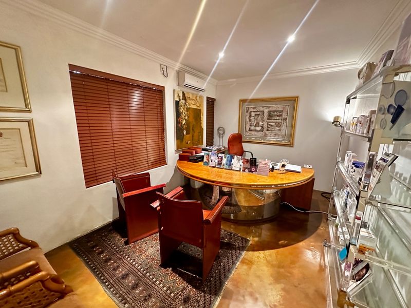 A functional office space featuring polished concrete flooring, wooden venetian blinds, and a wall-mounted air conditioning unit.