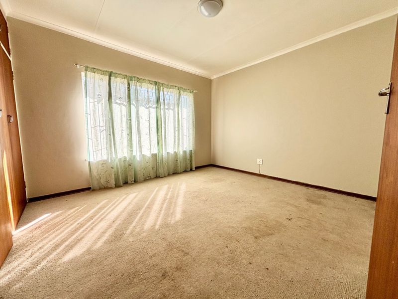 An empty bedroom featuring neutral walls, coved ceilings, and carpeted flooring, offering a blank canvas for potential interior design updates.