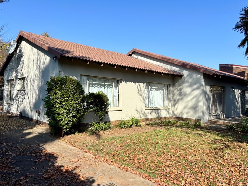 Front elevation of a single-story house featuring a tiled roof, plastered exterior walls, and a concrete driveway.