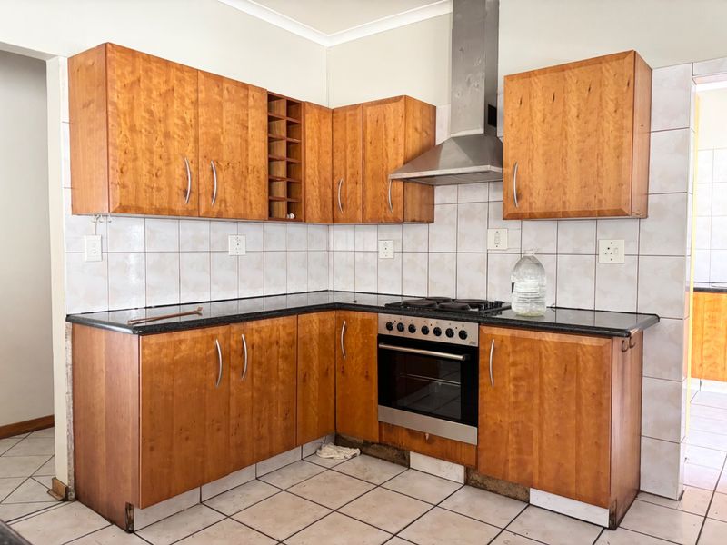 A functional kitchen featuring wooden cabinetry, granite countertops, and built-in appliances, requiring minor repairs to the base cabinetry kickplates.