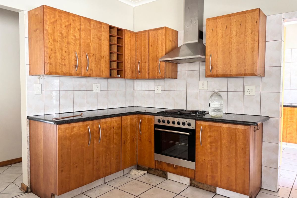 A functional kitchen featuring wooden cabinetry, granite countertops, and built-in appliances, requiring minor repairs to the base cabinetry kickplates.